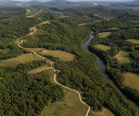 Aerial view of Elk River Hills gravel road winding alongside the river through Ozark valleys