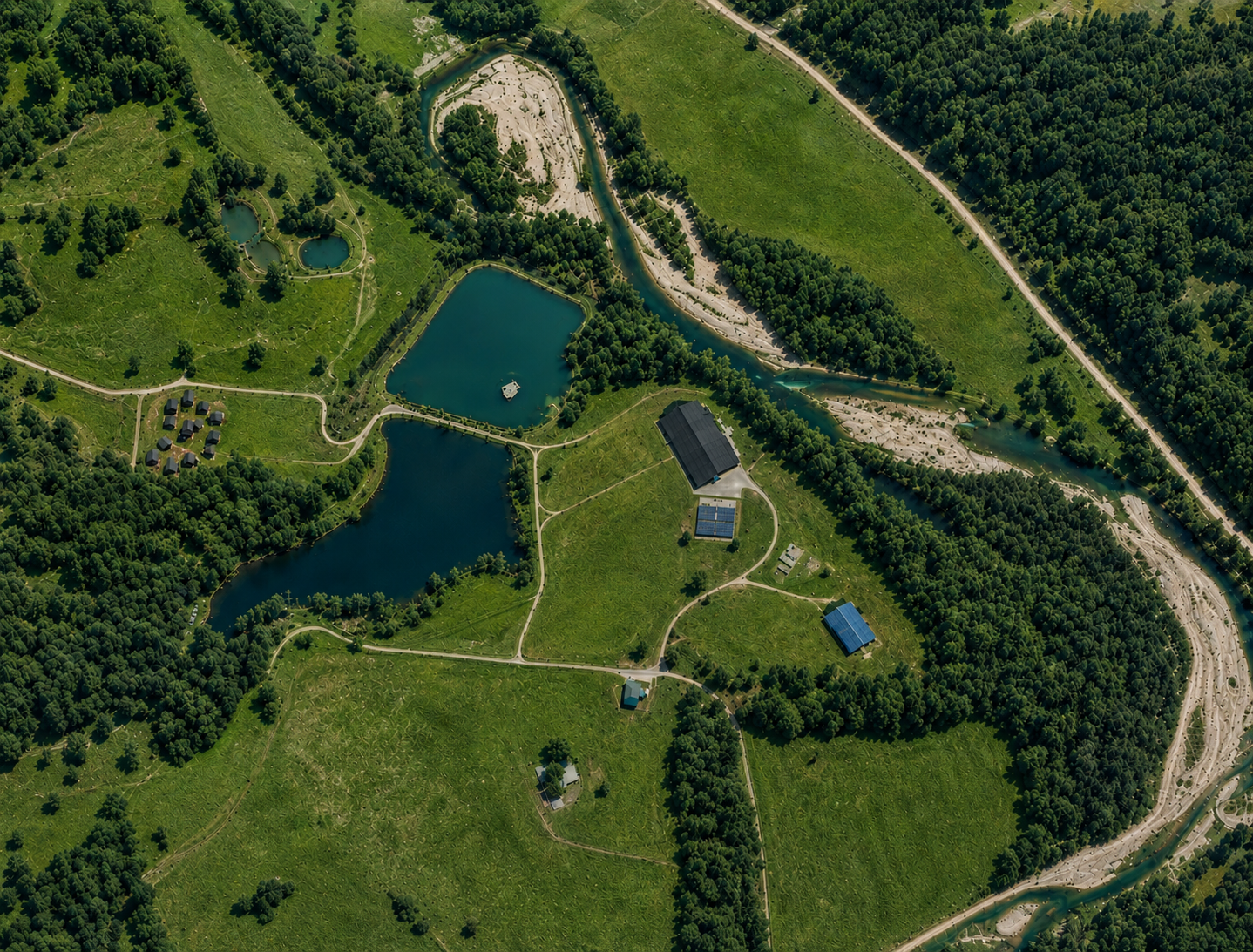 Aerial view of Ozark Adventure Club showing Olympic Village Cabins, spring-fed lake, and Ozark ridgelines